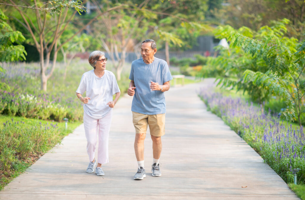 A senior man and a woman smiling while walking in a park